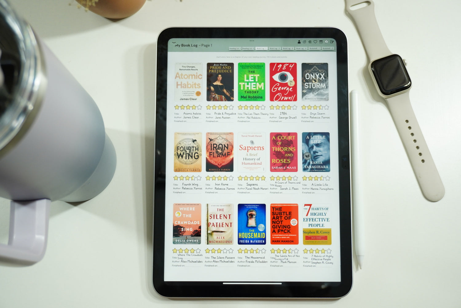 Book log page of the digital reading journal open in an iPad, lying on a study table with an apple watch and a stanley mug next to it.